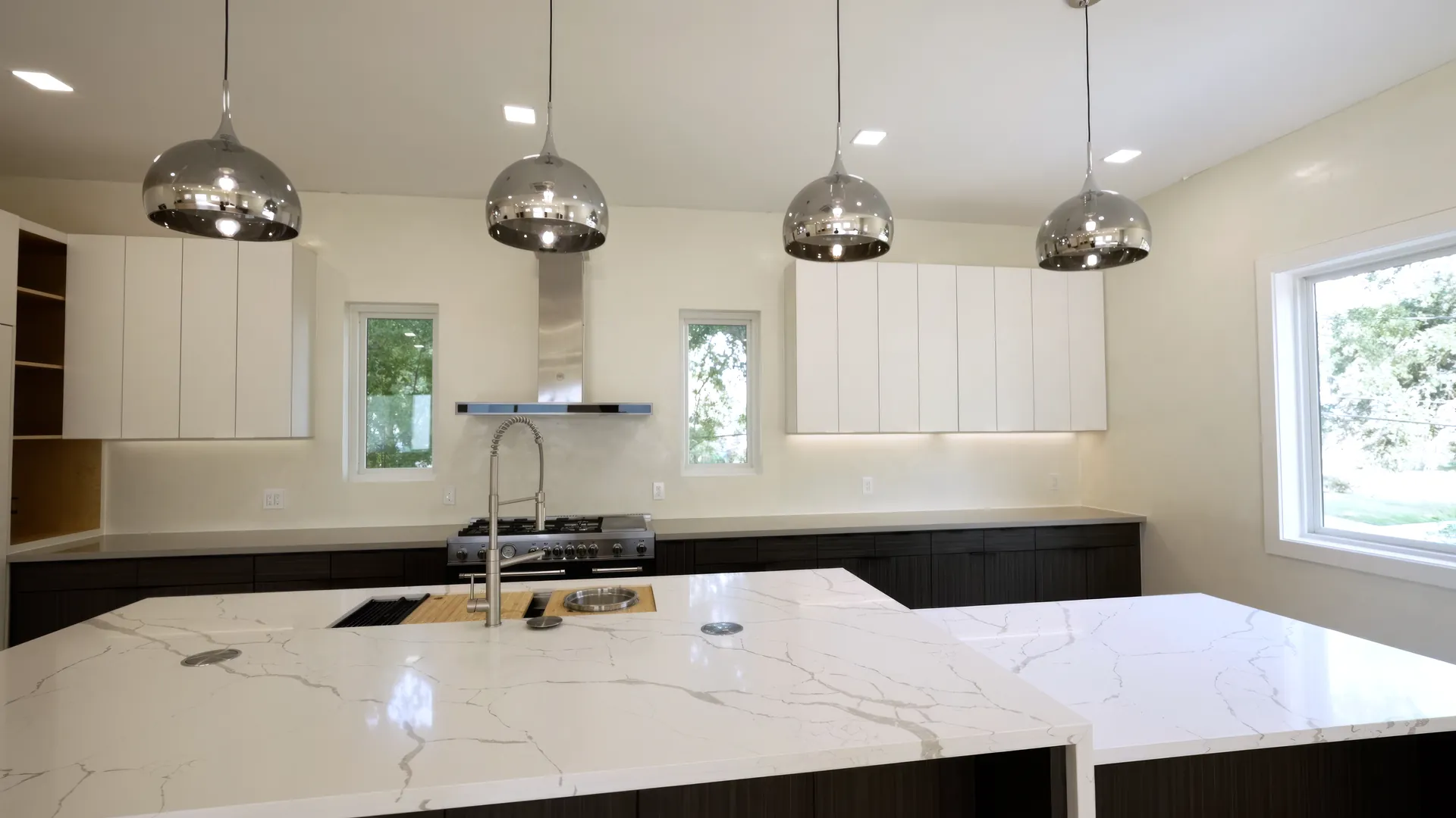 The finished kitchen: cabinetry, stone island, and pendant lighting installed
